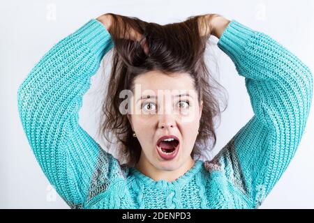 Fille pop-eyed dans un shok à la bouche ouverte et debout les cheveux, sur un fond blanc. Banque D'Images