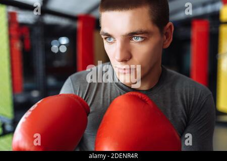 Boxeur masculin engagé dans l'entraînement dans la salle de gym, dans une cage pour un combat sans règles Banque D'Images