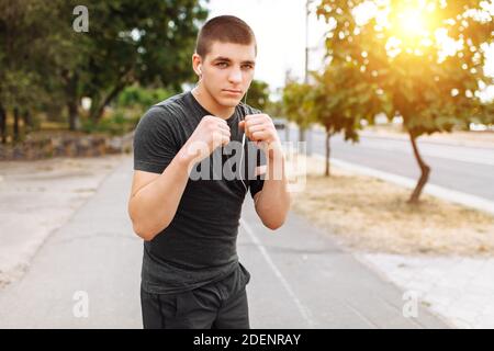 Un jeune homme accomplit des coups dans la rue, l'entraînement du matin avant la boxe Banque D'Images