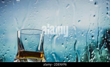 Un verre de whisky, whisky sur la barre près de la fenêtre, descend le long du verre. Banque D'Images