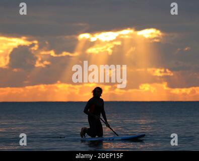 surfeurs attendant sur l'eau pour une vague dans le coucher de soleil Banque D'Images