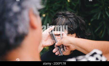 Photo de la jeune femme qui obtient sa coupe de cheveux. Le coiffeur utilise des ciseaux et un peigne. Banque D'Images