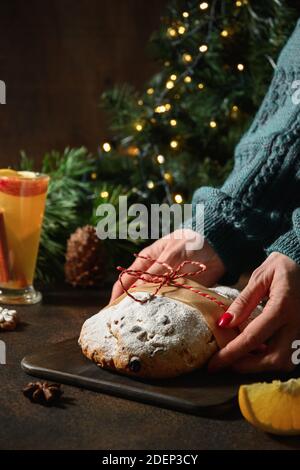 Une femme a servi Chistmas stollen sur fond marron guirlande décorée et branches à feuilles persistantes. Banque D'Images