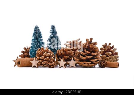 Arrangement de Noël avec des cônes de pin de saison, de petits arbres de Noël, des ornements en bois et des bâtons de cannelle sur fond blanc Banque D'Images