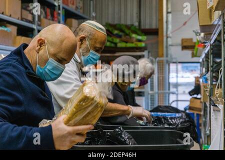 Toronto, Canada. 25 novembre 2020. Les bénévoles qui portent des masques préparent des repas à la Chasdei Kaduri Jewish Food Bank.c'est la seule organisation juive entièrement gérée par des bénévoles, qui se consacre à la livraison hebdomadaire d'aliments non périssables, de produits de boulangerie frais et de produits à des centaines de familles juives nécessiteuses dans la région du Grand Toronto. Depuis la pandémie de Covid-19 en mars 2020, la demande de services a considérablement augmenté. Crédit : Shawn Goldberg/SOPA Images/ZUMA Wire/Alay Live News Banque D'Images