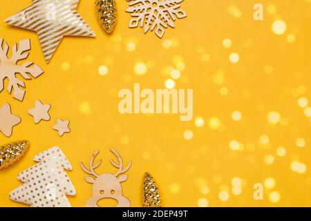 Belle carte postale de Noël ou du nouvel an avec verre, textile, décorations en bois sur fond jaune avec lumières. Vue de dessus de la mise à plat avec espace de copie Banque D'Images