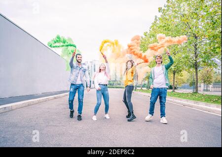 Des jeunes souriants et heureux qui se présentent dans la rue avec une couleur Signal fusée dans la main - concept d'amitié heureux avec les jeunes étudiants ont un toget amusant Banque D'Images