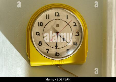 Ancienne horloge électrique jaune sale accrochée au mur Banque D'Images
