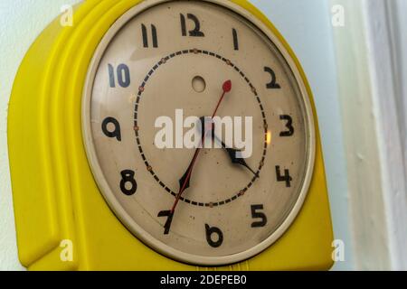 Ancienne horloge électrique jaune sale accrochée au mur Banque D'Images