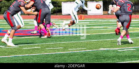 Quarterback Laterback lancer le football à son dos de course tandis que la ligne offensive bloque suring un match de football. Banque D'Images