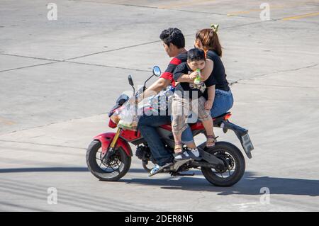 SAMUT PRAKAN, THAÏLANDE, JUL 27 2020, le couple fait une moto avec un garçon suspendu dans les bras de sa mère. Banque D'Images