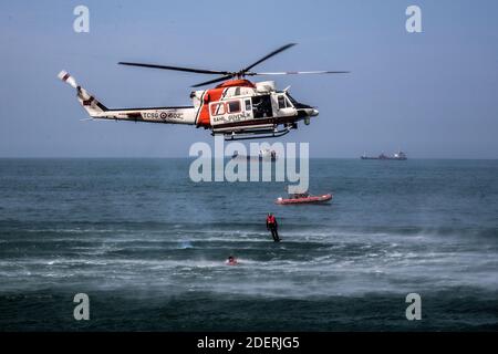 L'hélicoptère de sauvetage effectuant une opération de sauvetage en mer est dans l'air. Un officier saute dans la mer. Banque D'Images