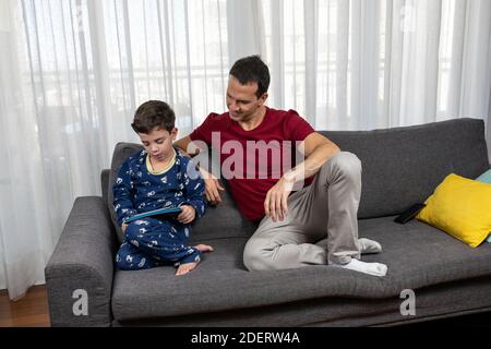 Homme mature (44 ans) assis à côté de son fils (6 ans) et lui souriant. Banque D'Images