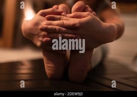 Femme courte pieds nus faisant place à la posture du coude avant pendant le yoga leçon la nuit Banque D'Images