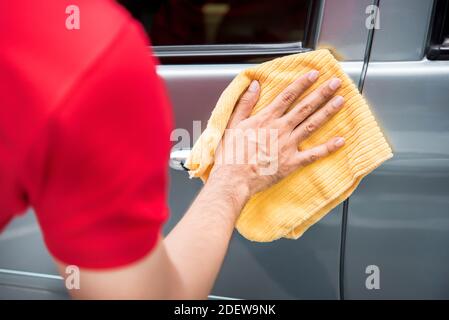 Le personnel du service d'entretien automobile pour hommes nettoie la porte de la voiture avec une microfibre tissu Banque D'Images
