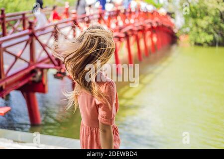 Femme de race blanche voyageur sur fond de Red Bridge en public parc jardin avec arbres et réflexion au milieu de Lac Hoan Kiem dans le centre-ville de Hanoi Banque D'Images