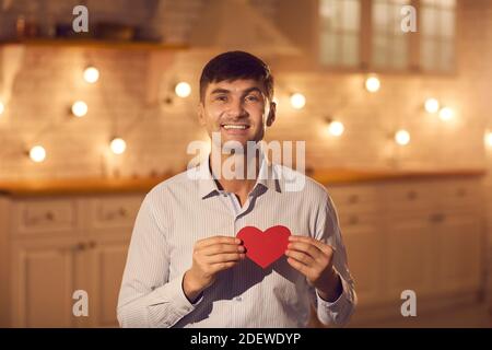 Homme souriant petit ami montrant rouge coeur décoratif à sa petite amie pendant les rencontres en ligne Banque D'Images