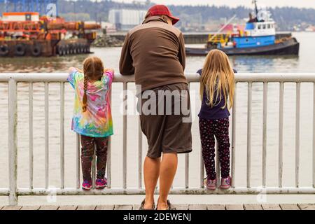 Vue arrière d'un père avec ses deux filles sur la jetée à New Westminster, C.-B., Canada. 29 septembre 2020. Mise au point sélective, photo de voyage, vue sur la rue Banque D'Images