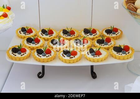 Tartelettes mini-dessert avec fruits frais sur support. Banque D'Images