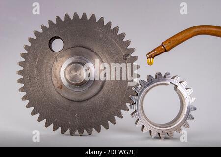 Lubrifier les pignons métalliques avec de l'huile pour engrenages. Pièces de rechange utilisées dans les ateliers automobiles. Arrière-plan clair. Banque D'Images