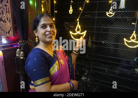 Mumbai / Inde 14 novembre 2020 UNE femme mariée indienne souriante en robe traditionnelle sari tenant LED Diya à l'occasion de Diwali. Banque D'Images
