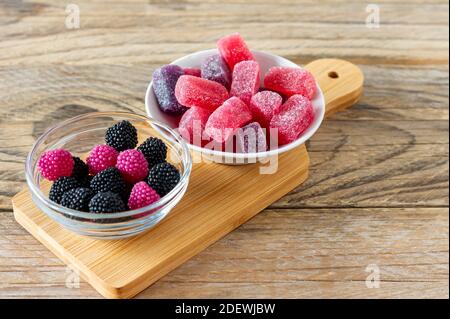 Mâcher des bonbons en gelée de confiture de marmelade aux saveurs de baies sur une table en bois. Banque D'Images