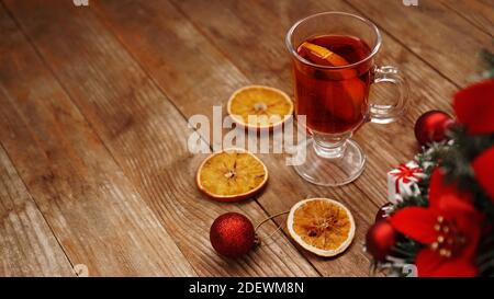 Vin chaud de Noël dans une tasse de verre sur une table en bois avec des oranges sèches Banque D'Images