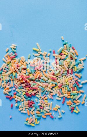 Une poignée de nouilles de couleur sucrée déversées sur une table bleue. Banque D'Images