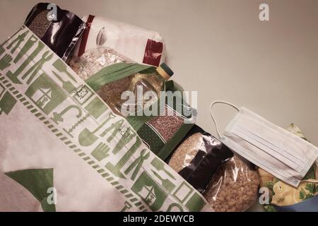Approvisionnement alimentaire de crise pour la période d'isolement en quarantaine pendant la pandémie du coronavirus. Un ensemble de produits dans un sac en papier : riz, pâtes, flocons d'avoine, sug Banque D'Images