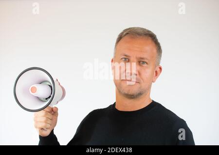 Jeune homme tenant un mégaphone sur fond blanc Banque D'Images