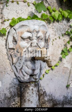 Eau potable fraîche disponible à partir d'une fontaine avec un visage sculpté orné dans la ville de Ravello Campania Italie. Banque D'Images