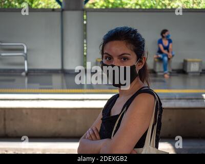 La femme latine avec masque de protection noir attend le Station de métro ennuyeuse Banque D'Images