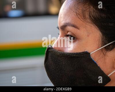 La femme latine avec masque de protection noir attend le Station de métro ennuyeuse Banque D'Images