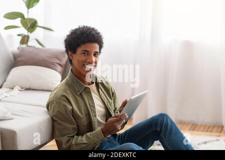 Concept de homeschooling. Positif noir adolescent gars avec tablette informatique étudiant à distance de la maison, espace vide Banque D'Images