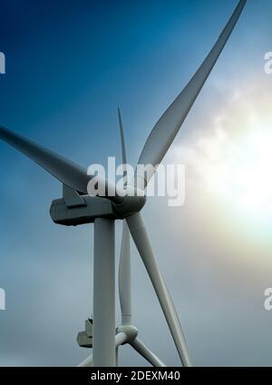 Éoliennes générant de l'électricité verte dans une tempête avec des nuages sombres et le soleil se brise. Banque D'Images