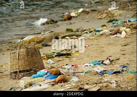 Les objets projetés en arrière par la mer s'est échoué sur une plage de sable fin au Vietnam. Panier tressé en premier plan, sacs en plastique, les déchets et la mer en arrière-plan. Banque D'Images