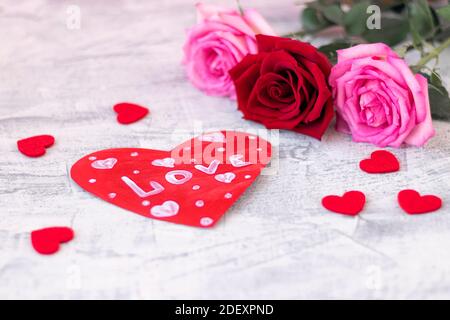 Valentin fait main sous forme de coeur avec l'inscription amour sur fond de pierre blanche avec peu de coeur rouge et bouquet de roses. Mise au point douce. Banque D'Images