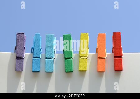 Sept épingles en bois multicolores, peintes dans les couleurs de l'arc-en-ciel, contre le ciel bleu. Banque D'Images