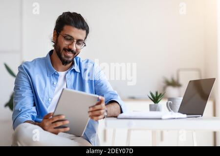Un travailleur indépendant indien utilisant une tablette numérique à la maison, ayant fait une pause au travail Banque D'Images