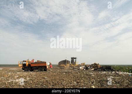 Tri des déchets dans la décharge de la grande ville. Beaucoup de déchets. Chariot avec manipulateur hydraulique manuel. Tracteur jaune. Banque D'Images