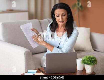 Femme dans un micro-casque assis au bureau, ayant un magnétoscope sur un ordinateur portable Banque D'Images