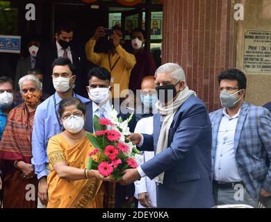 Une femme portant un masque de visage offre un bouquet de fleurs au gouverneur, Jagdeep Dhankar lors de la cérémonie d'inauguration.le gouverneur du Bengale occidental, Jagdeep Dhankar, inaugure le lancement du troisième essai de phase de Covaxine au Conseil indien de la recherche médicale (CIMR) à Kolkata. Banque D'Images