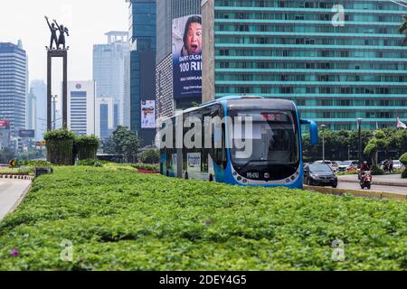 Jakarta / Indonésie - 25 octobre 2020. Un bus bleu transjakarta articulé qui traverse le rond-point de l'hôtel indonésien sur fond de ciel Banque D'Images