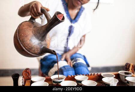 Gros plan de la main de womans comme elle sert le café d'un pot traditionnel en Ethiopie. Banque D'Images