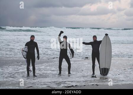 Surfeurs de l'Arctique qui passent par la plage après le surf Banque D'Images