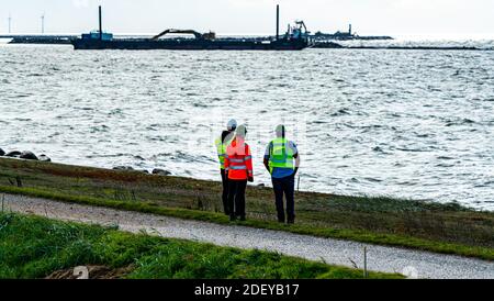 Inspecteurs portant des gilets réfléchissants et des casques de sécurité supervisant un chantier de construction. Banque D'Images