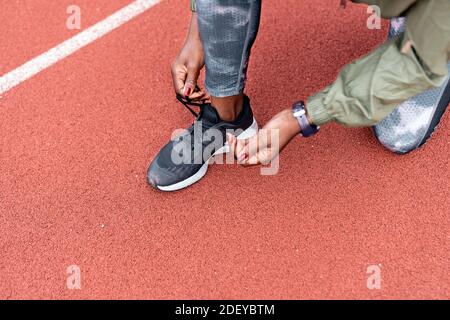 Photo d'un sprinter afro-américain méconnu qui noue ses sports les chaussures se noue sur une piste d'athlétisme Banque D'Images