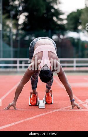 Photo d'un sprinter afro-américain en position de départ commencez à courir sur un circuit d'athlétisme Banque D'Images