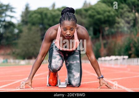 Photo d'un sprinter afro-américain en position de départ commencez à courir sur un circuit d'athlétisme Banque D'Images