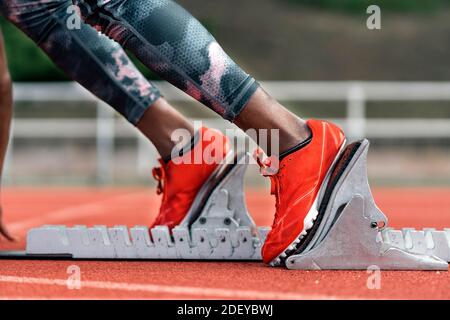 Photo d'un sprinter afro-américain méconnaissable en position de départ pour commencer à courir sur un circuit d'athlétisme Banque D'Images